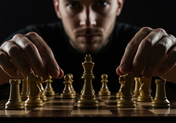A person strategically moving chess pieces on a board